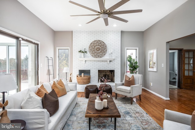 living room featuring ceiling fan, wood-type flooring, and a fireplace