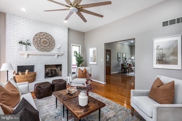 living room featuring ceiling fan, a brick fireplace, and hardwood / wood-style floors