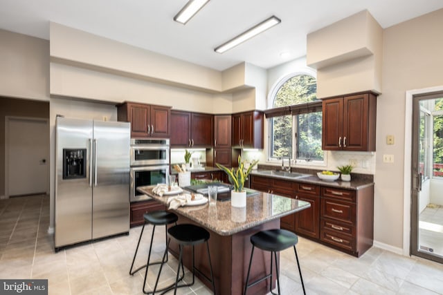 kitchen featuring a center island, a healthy amount of sunlight, stainless steel appliances, and a breakfast bar area