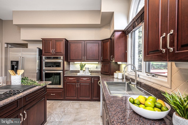 kitchen with tasteful backsplash, appliances with stainless steel finishes, sink, and dark stone counters