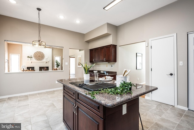 kitchen with a kitchen island, a kitchen breakfast bar, hanging light fixtures, dark brown cabinetry, and a fireplace