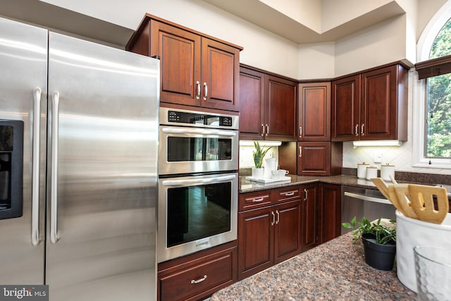 kitchen featuring dark stone countertops, backsplash, and stainless steel appliances