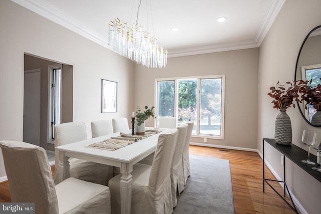 dining room with hardwood / wood-style floors, crown molding, and a chandelier