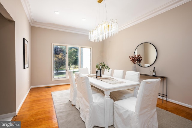 dining space with crown molding, a notable chandelier, and light wood-type flooring