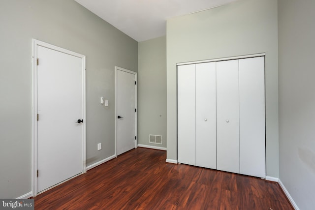 unfurnished bedroom featuring dark wood-type flooring and a closet