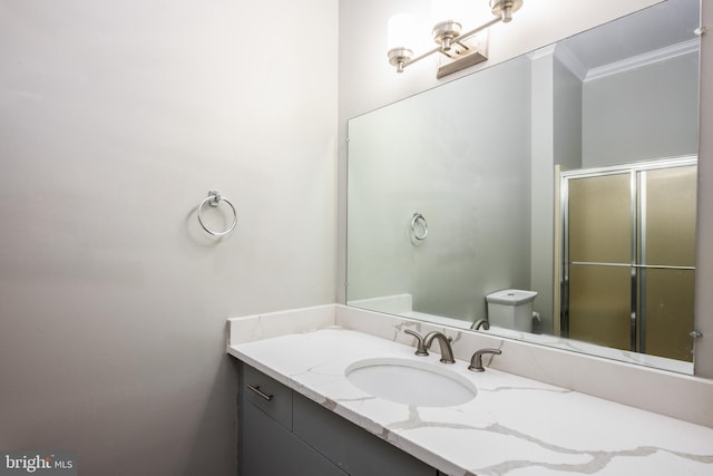 bathroom with vanity, crown molding, a shower with shower door, and toilet