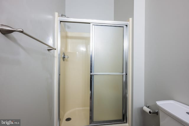 bathroom with a shower with door and toilet