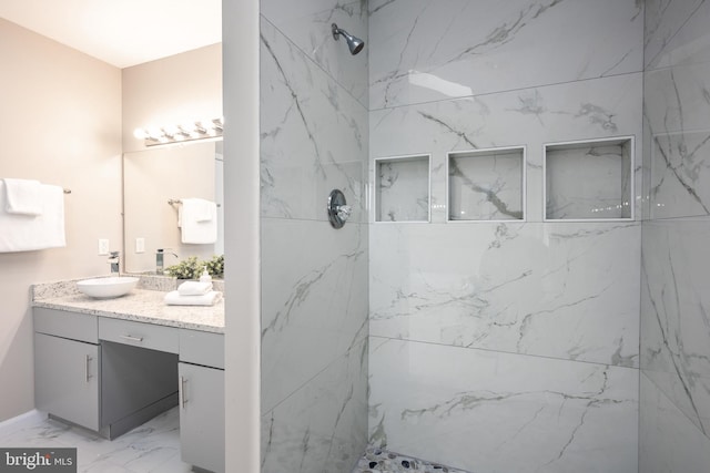 bathroom with a tile shower and vanity