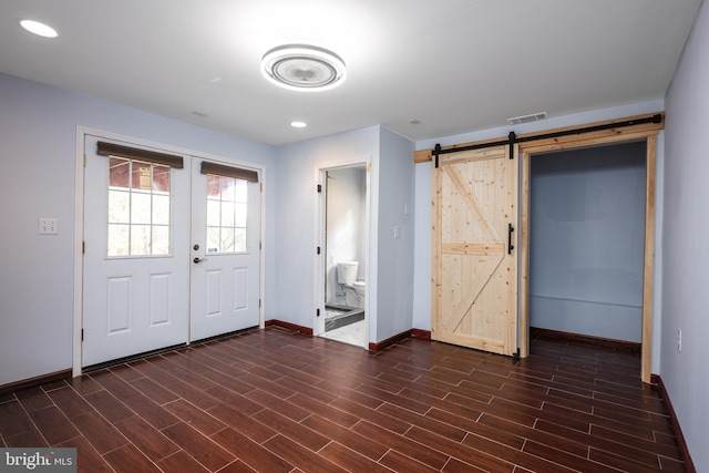 entryway featuring french doors, dark hardwood / wood-style floors, and a barn door