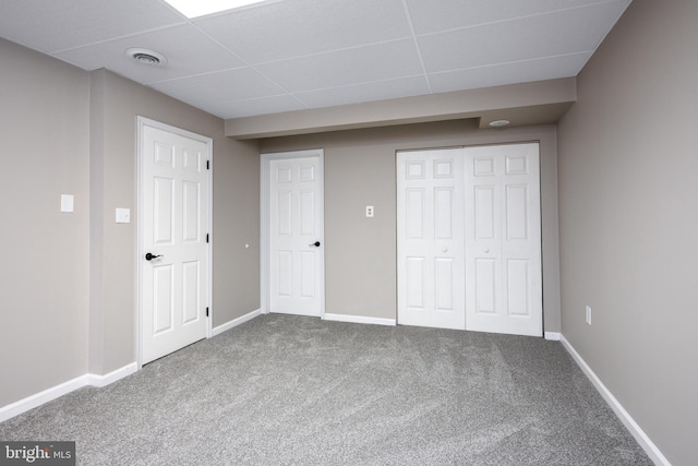 unfurnished bedroom with a drop ceiling and carpet flooring