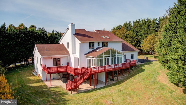 back of property with a wooden deck, a yard, a patio area, and a sunroom