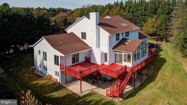 rear view of property featuring a wooden deck, a patio area, a sunroom, and a lawn