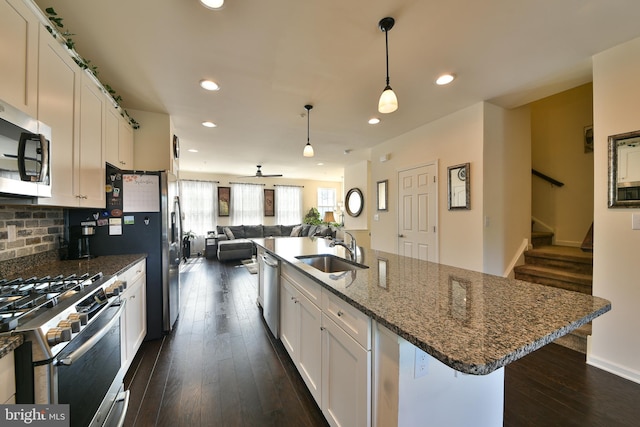 kitchen with white cabinetry, dark stone counters, dark hardwood / wood-style floors, stainless steel appliances, and sink