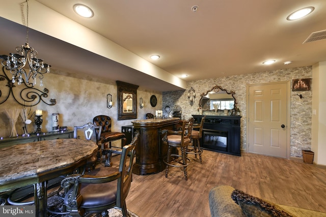 bar with a notable chandelier, a fireplace, and hardwood / wood-style floors