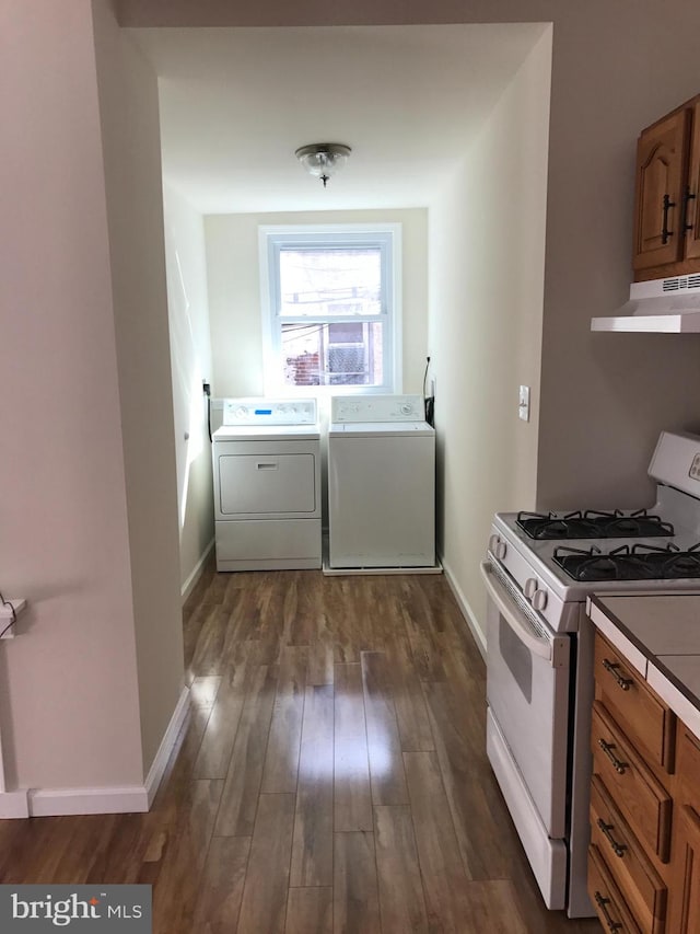 kitchen with exhaust hood, white gas range oven, dark hardwood / wood-style floors, and washing machine and clothes dryer