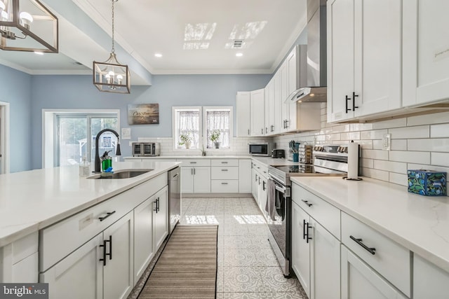 kitchen featuring pendant lighting, white cabinets, sink, wall chimney exhaust hood, and stainless steel appliances