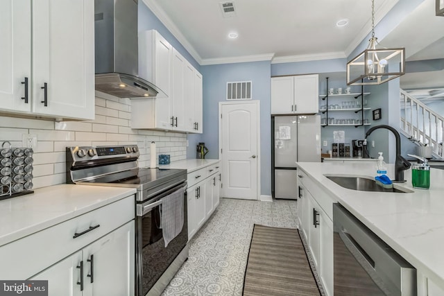 kitchen with pendant lighting, wall chimney range hood, sink, appliances with stainless steel finishes, and white cabinetry