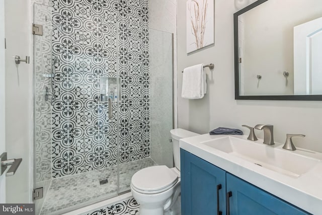 bathroom featuring vanity, toilet, and a shower with shower door