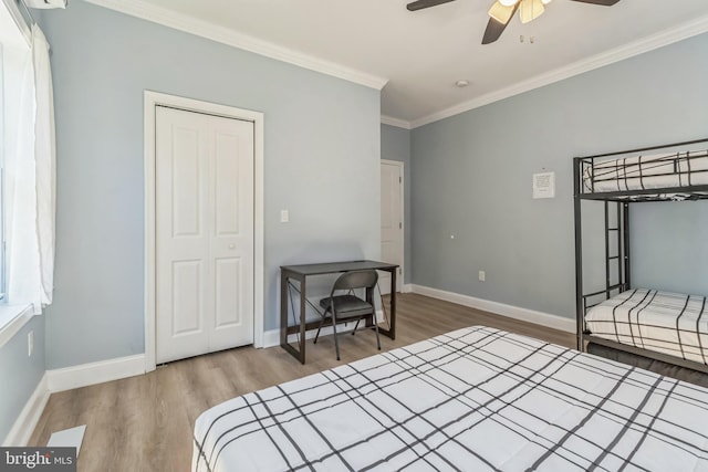 bedroom featuring a closet, ceiling fan, crown molding, and wood-type flooring