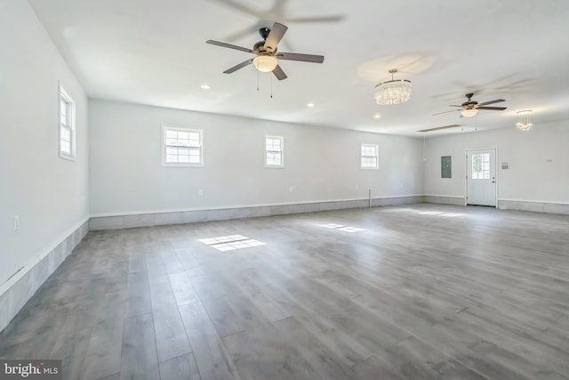 unfurnished room with ceiling fan with notable chandelier, light hardwood / wood-style floors, and electric panel