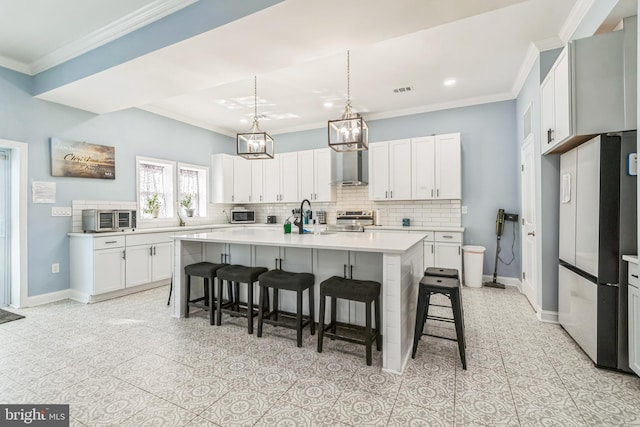 kitchen with a kitchen bar, appliances with stainless steel finishes, white cabinetry, and a kitchen island with sink