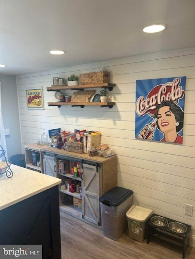 bar with hardwood / wood-style flooring and wooden walls