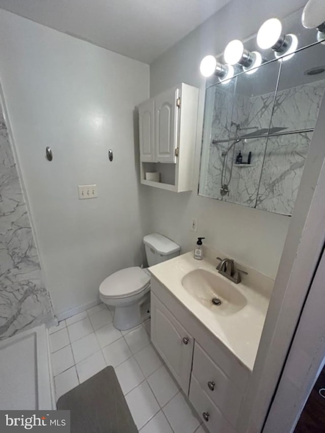 bathroom with vanity, toilet, tile patterned floors, and tiled shower