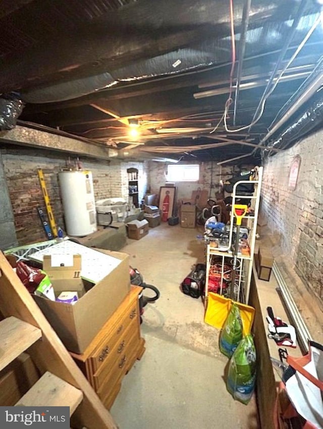 basement featuring water heater and brick wall