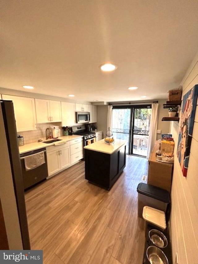 kitchen featuring a center island, white cabinetry, stainless steel appliances, and light wood-type flooring