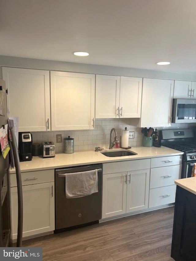 kitchen featuring dark hardwood / wood-style floors, sink, white cabinetry, appliances with stainless steel finishes, and tasteful backsplash