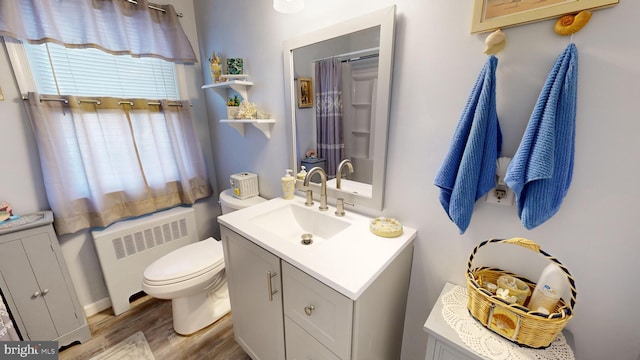 bathroom featuring vanity, wood-type flooring, radiator heating unit, and toilet