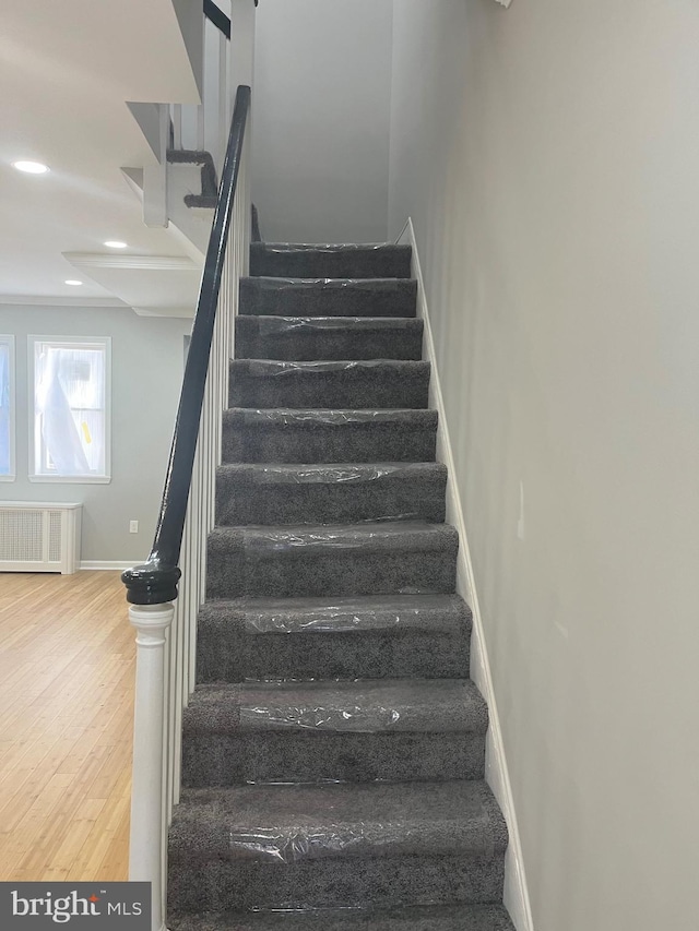 stairs with hardwood / wood-style floors and radiator