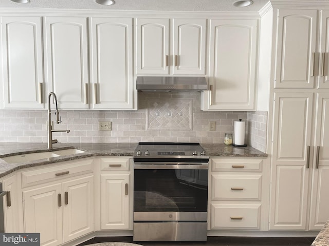 kitchen featuring stainless steel range with electric cooktop, dark stone counters, sink, and white cabinetry