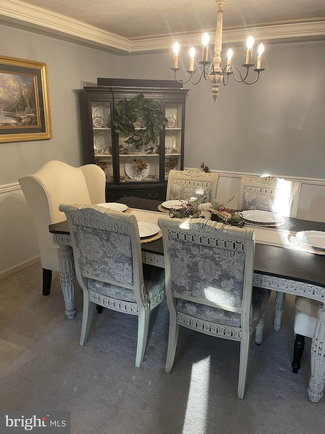 dining space featuring carpet, ornamental molding, an inviting chandelier, and a textured ceiling