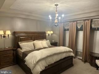 bedroom featuring light carpet and an inviting chandelier