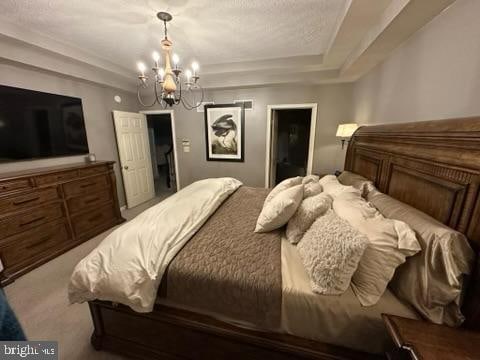 carpeted bedroom with a notable chandelier and a tray ceiling