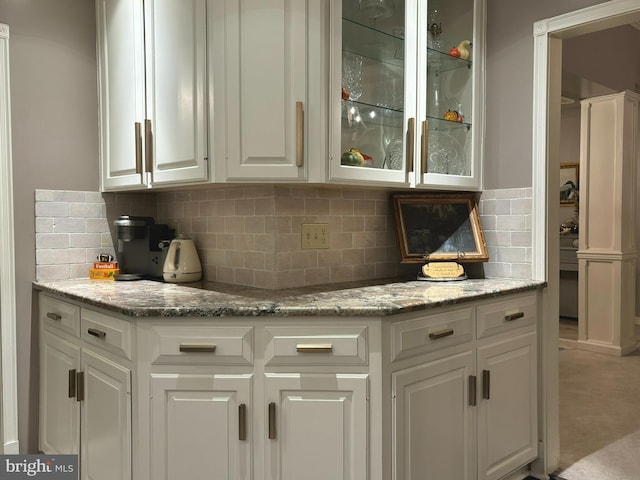 bar with light stone counters, light colored carpet, backsplash, and white cabinetry