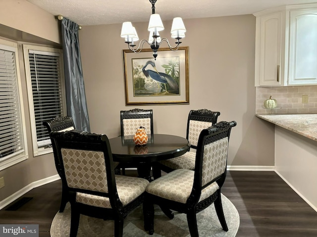 dining area with a textured ceiling, a chandelier, and dark hardwood / wood-style flooring