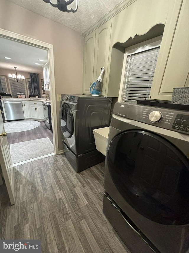 laundry area featuring an inviting chandelier, cabinets, washer and clothes dryer, hardwood / wood-style flooring, and a textured ceiling