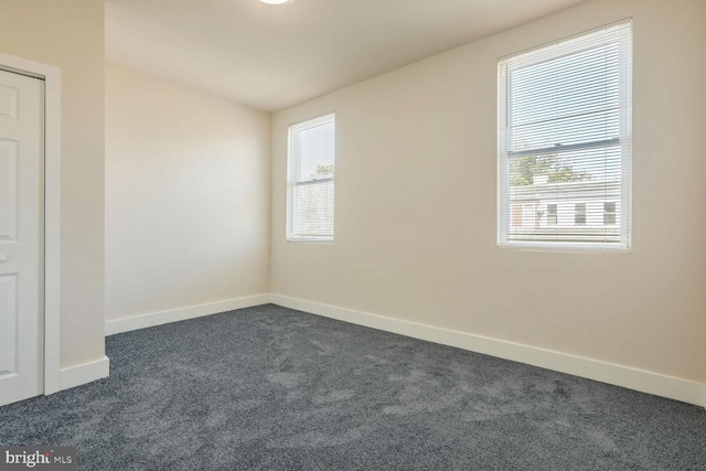 unfurnished room with dark colored carpet