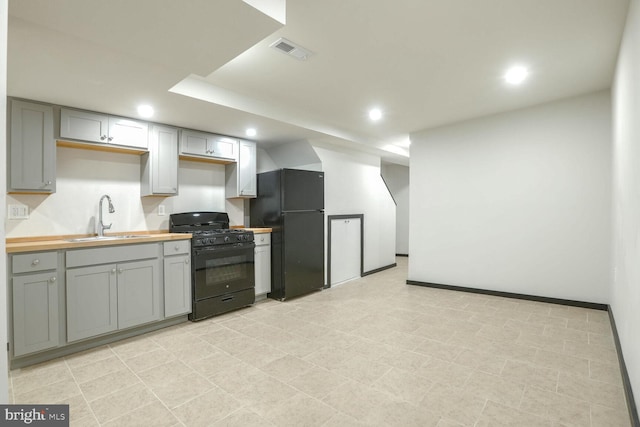 kitchen featuring gray cabinets, wood counters, black appliances, and sink