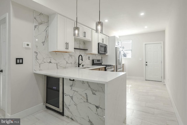 kitchen with appliances with stainless steel finishes, sink, kitchen peninsula, decorative light fixtures, and white cabinets