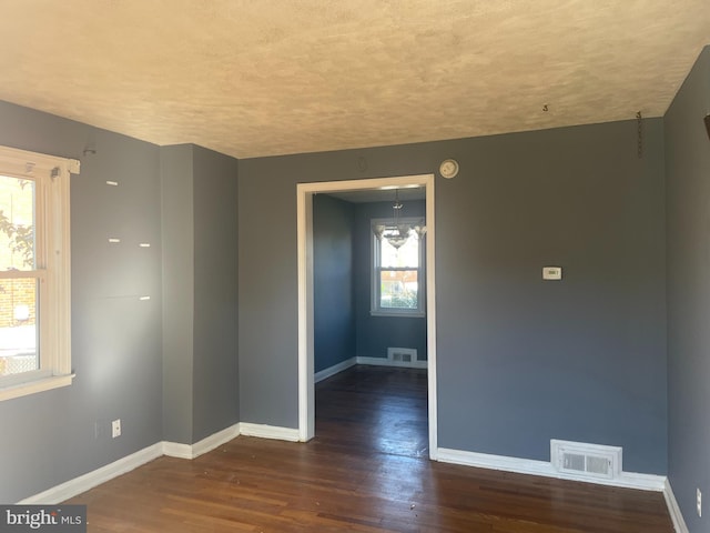 unfurnished room featuring a wealth of natural light and dark hardwood / wood-style flooring