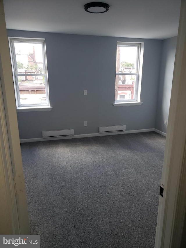 carpeted empty room featuring a healthy amount of sunlight and a baseboard heating unit