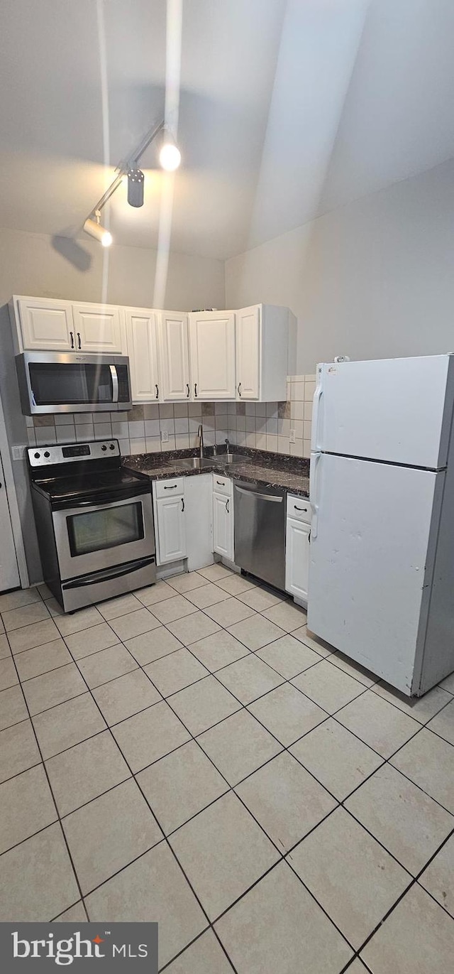 kitchen with white cabinets, track lighting, high vaulted ceiling, backsplash, and appliances with stainless steel finishes