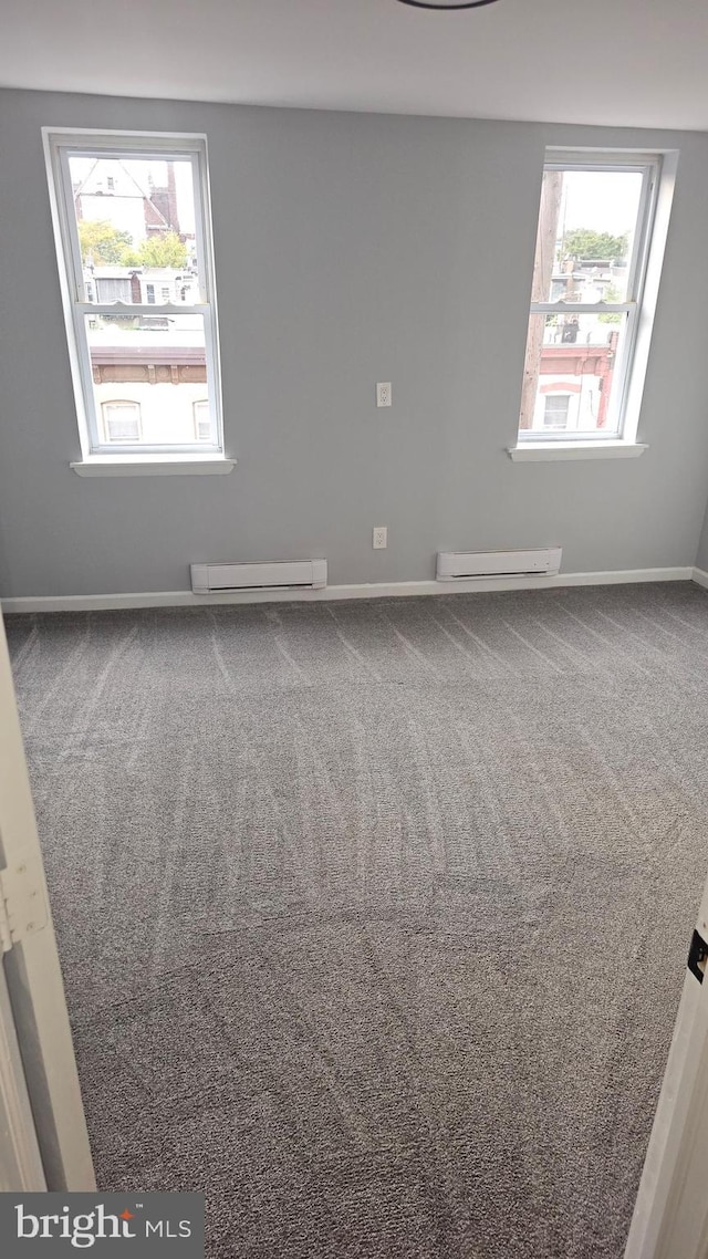 carpeted spare room featuring a baseboard heating unit