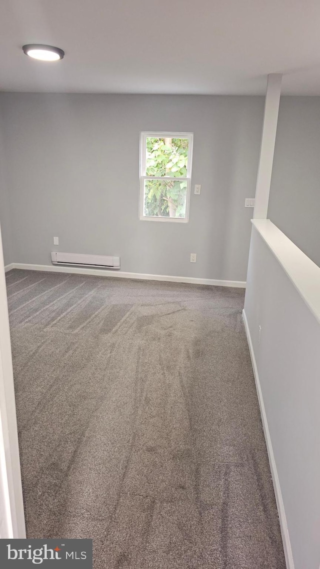 empty room featuring a baseboard heating unit and carpet