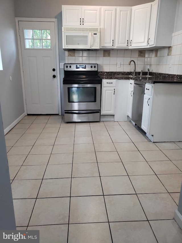 kitchen with tasteful backsplash, white cabinets, light tile patterned floors, and stainless steel appliances