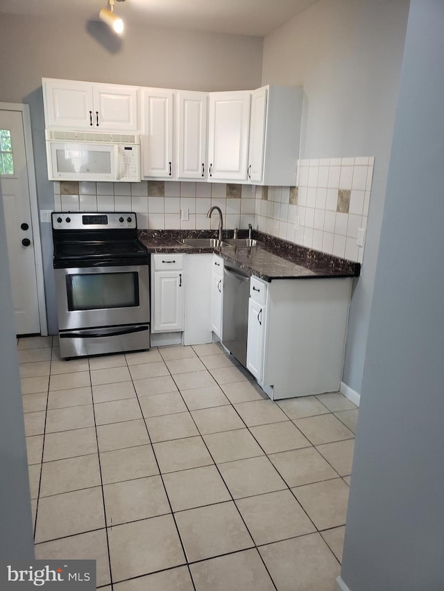 kitchen featuring tasteful backsplash, appliances with stainless steel finishes, light tile patterned floors, and white cabinets