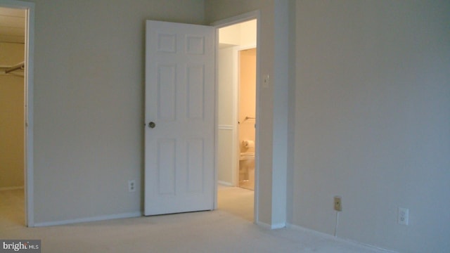 unfurnished bedroom featuring light colored carpet, a spacious closet, and a closet